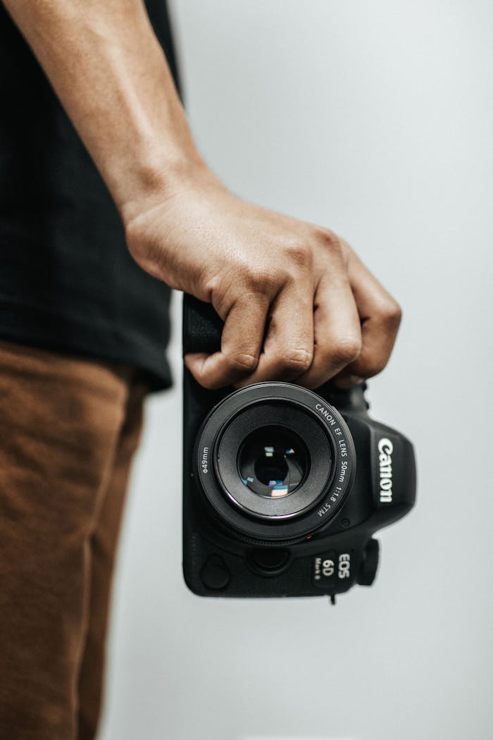 A close-up shot of a hand holding a DSLR camera, ideal for photography concepts.