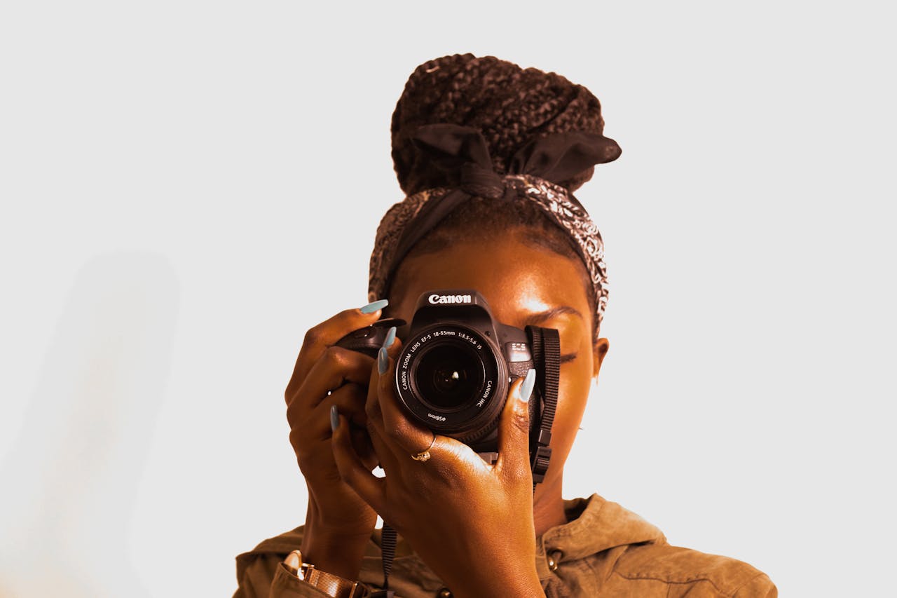 client-stories-img Portrait of a woman holding a DSLR camera with braided hair and bandana.