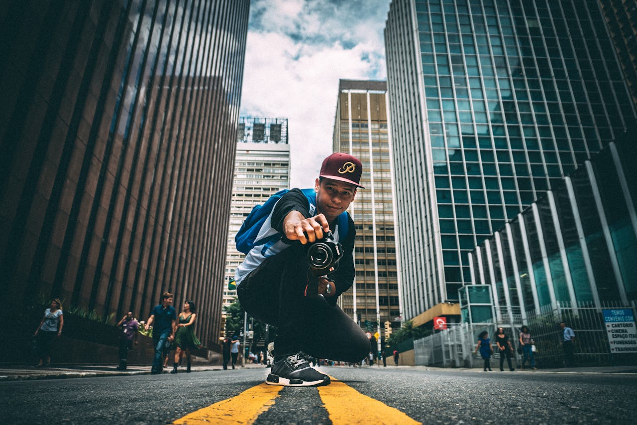 Crafting Captivating Headlines: Your awesome post title goes here A young man with a camera kneels on a bustling city street, surrounded by skyscrapers.